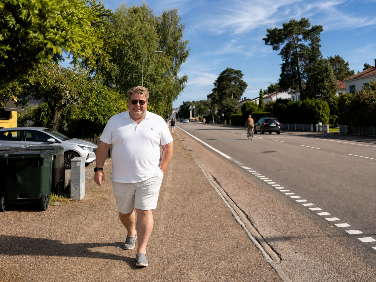 Pierre Gustafsson på en trottoar längs en genomfartsgata i Ängelholm där en cyklist och bilar passerar